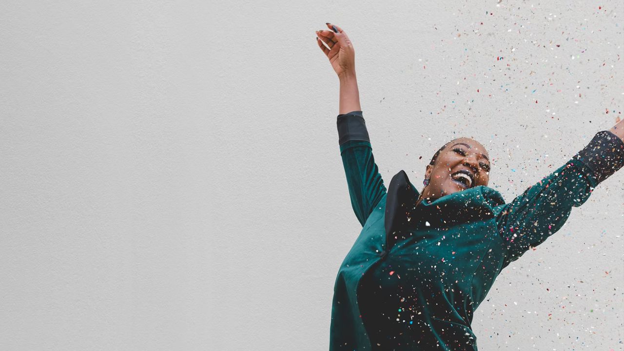 women raising her arms covered in confetti, celebrating